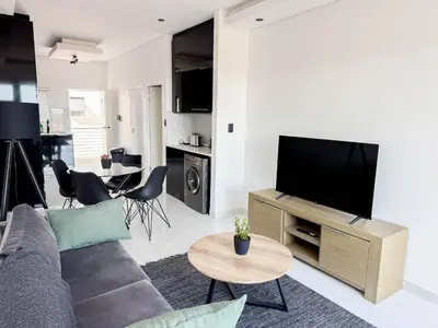 a living room with a couch and a flat screen tv at Greystone Executive Apartments in Cape Town