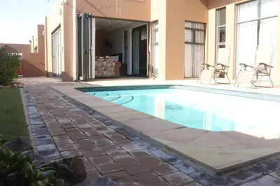a swimming pool in front of a house at Trinity in Cape Town