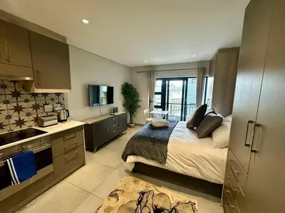a bedroom with a bed and a kitchen with at The Den at 41- Parking included in Stellenbosch