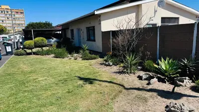 a house with a grass yard in front of it at Leisure Lodges Middle Room in Cape Town