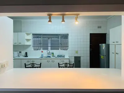 a kitchen with two chairs and a refrigerator at Leisure Lodges Middle Room in Cape Town