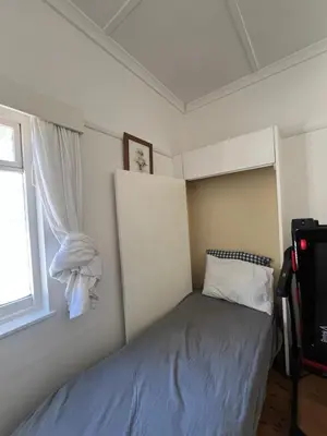 a small bedroom with a bed and a window at Lala Panzi House - Grotto Beach, Voëlklip in Hermanus