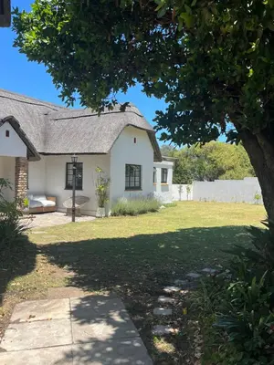 a white house with a tree in the yard at Lala Panzi House - Grotto Beach, Voëlklip in Hermanus