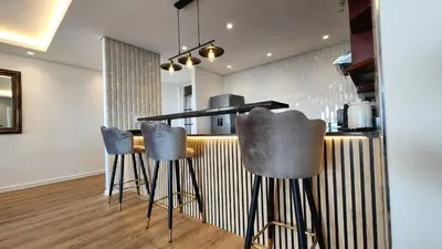 a kitchen with three bar stools in front of a counter at Capri 504, Island Club, Century City in Cape Town