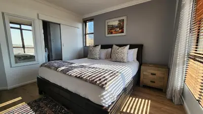 a bedroom with a bed in a room with windows at Capri 504, Island Club, Century City in Cape Town
