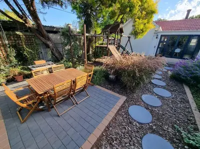 a patio with a wooden table and chairs at Spacious Lanes Cottage and Garage Parking in Cape Town
