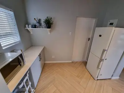 a kitchen with a white refrigerator and a wooden floor at Spacious Lanes Cottage and Garage Parking in Cape Town