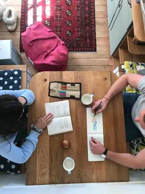 two people sitting at a wooden table with a tableablishangering at Babylons Tower Shepherds Hut in Mosselrivier