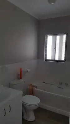 a bathroom with a toilet and a tub and a window at no 5 King Street, Onrus in Hermanus