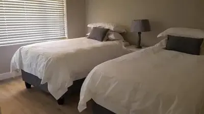 two white beds in a bedroom with a window at no 5 King Street, Onrus in Hermanus