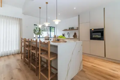 a kitchen with a large white island with wooden chairs at Maison la Bruyere, 8p villa - heated pool, airco & hottub in Franschhoek