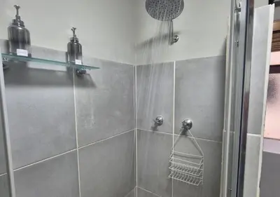 a bathroom with a shower with a glass door at A Short Walk to the Cliffs in Hermanus