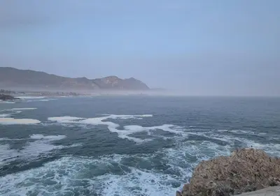 a view of the ocean with mountains in the distance at A Short Walk to the Cliffs in Hermanus