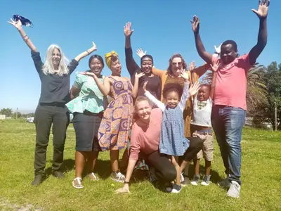 a group of people standing in a field with their arms in the air at Lighthouse Farm Backpackers Lodge in Cape Town