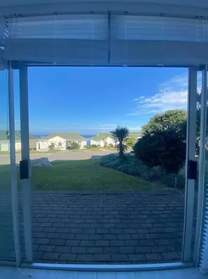 an open glass door of a house with a yard at 47 Whale Rock Estate in Hermanus