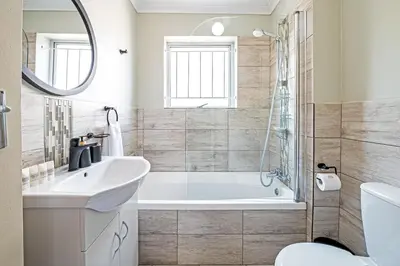 a bathroom with a tub and a sink and a mirror at Cozy Garden Unit in Bloubergstrand in Bloubergstrand