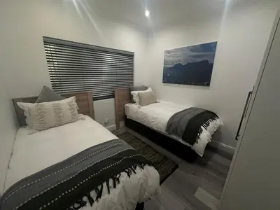 a bedroom with two beds and a window at Comfort Cove in Cape Town