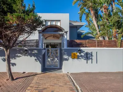 a house with a blue door and a tree at West Gemini Guesthouse in Cape Town