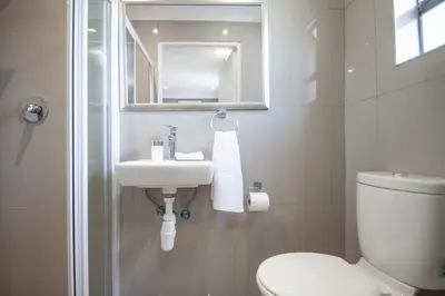 a white bathroom with a sink and a toilet at West Gemini Guesthouse in Cape Town