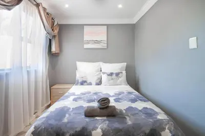 a bedroom with a bed with a blue and white comforter at West Gemini Guesthouse in Cape Town
