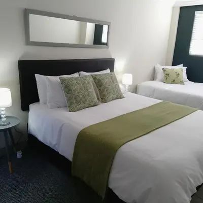 a bedroom with two beds and a mirror at 1 On Sonnet Unit Elaine in Cape Town