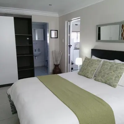 a bedroom with a large white bed and a bathroom at 1 On Sonnet Unit Elaine in Cape Town