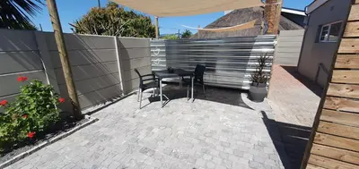 a patio with two chairs and a table and a fence at 1 On Sonnet Unit Elaine in Cape Town
