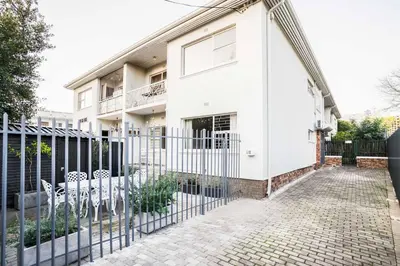 a white house with a fence in front of it at Avemore Vredehof 1 with backup power in Stellenbosch