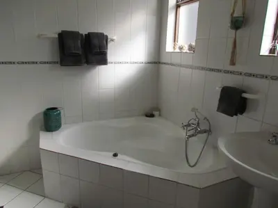 a white bathroom with a tub and a sink at The Beachside Nest in Cape Town