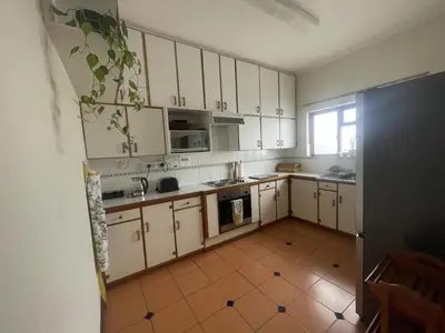 a kitchen with white cabinets and a tile floor at The Beachside Nest in Cape Town