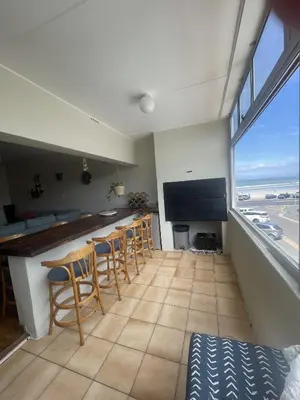a kitchen with a bar with chairs and a view of the ocean at The Beachside Nest in Cape Town