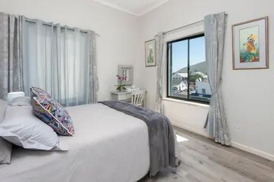 a white bedroom with a bed and a window at Seafront Penthouse - Marine Court Hermanus in Hermanus