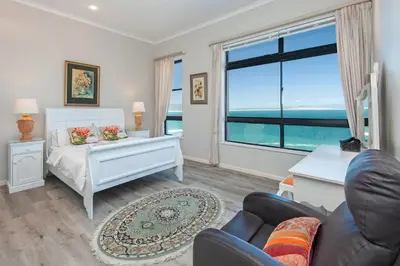 a bedroom with a bed and a large window at Seafront Penthouse - Marine Court Hermanus in Hermanus