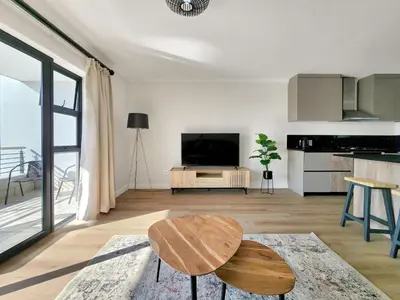 a living room with a table and a tv at Canal, Mountains, Sea Views, Pool, Gym, Parking, Wifi in Cape Town