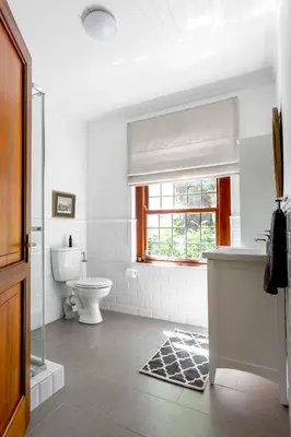a white bathroom with a toilet and a window at Keerweder Cottages in Franschhoek