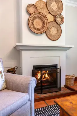 a living room with a fireplace with plates on the wall at Keerweder Cottages in Franschhoek
