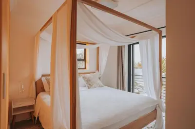a bedroom with a canopy bed with a window at Calm Blouberg Beach Apt - Gated & Lift Access in Cape Town