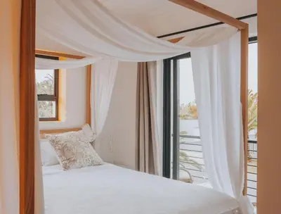 a bedroom with a canopy bed and a window at Calm Blouberg Beach Apt - Gated & Lift Access in Cape Town