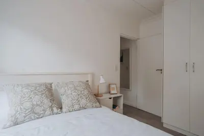 a bedroom with a white bed with a white headboard at Calm Blouberg Beach Apt - Gated & Lift Access in Cape Town
