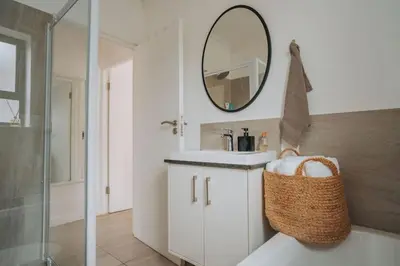 a bathroom with a sink and a mirror at Calm Blouberg Beach Apt - Gated & Lift Access in Cape Town