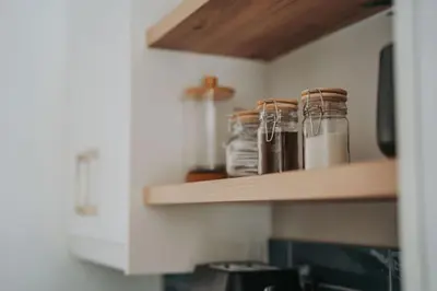 a kitchen shelf with glass jars on it at Calm Blouberg Beach Apt - Gated & Lift Access in Cape Town