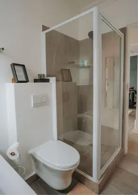a bathroom with a toilet and a glass shower at Calm Blouberg Beach Apt - Gated & Lift Access in Cape Town