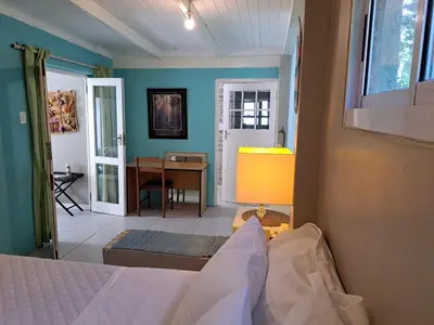 a bedroom with a bed and a table and a desk at The Willow Cottage in Cape Town