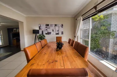 a wooden table with leather chairs and a large window at Magnificent House in Cape Town