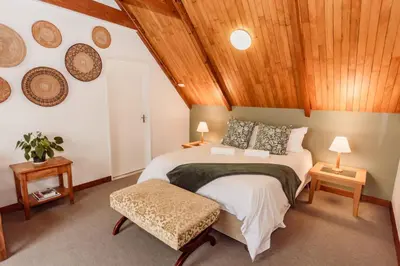 a bedroom with a large bed and wooden ceilings at The Attic - Deluxe Leisure Loft in Stellenbosch