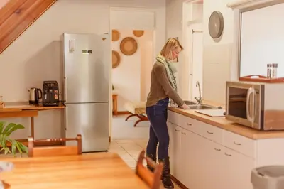 a woman standing in a kitchen next to a sink at The Attic - Deluxe Leisure Loft in Stellenbosch