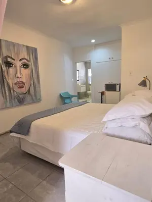 a bedroom with two beds and a painting on the wall at Red Door Strand Guest house in Cape Town