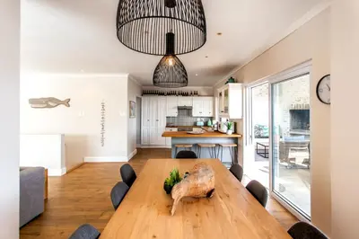 a kitchen and dining room with a wooden table at Sur La Mer in Hermanus