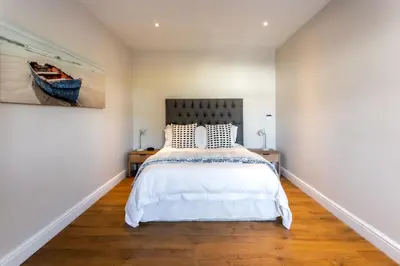 a bedroom with a bed and a painting on the wall at Sur La Mer in Hermanus