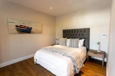 a bedroom with a bed and a painting of a boat at Sur La Mer in Hermanus